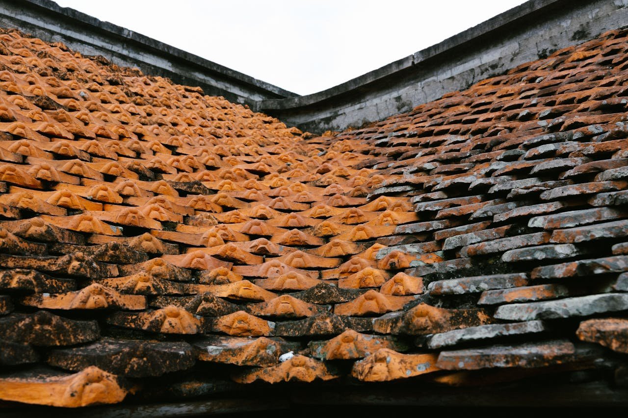 Detail of overlapping traditional orange clay roof tiles showing weathering and texture.